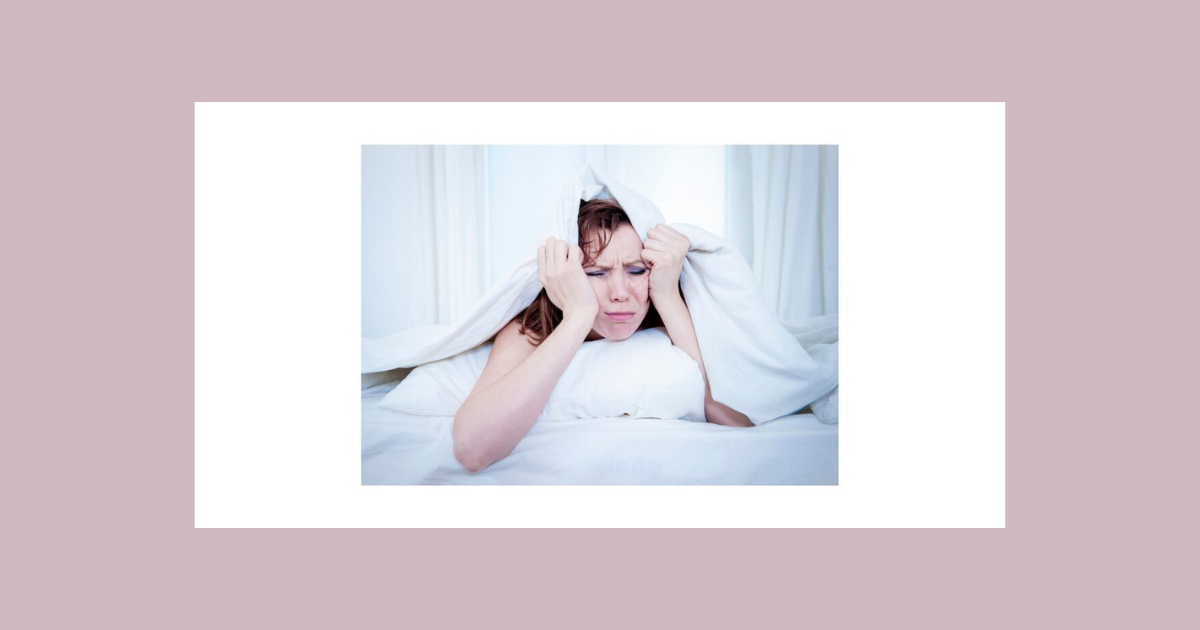 女性がベッドの中で眠れないという表情の画像